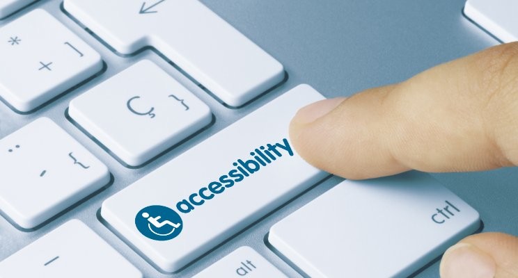 Finger hitting a button labeled accessibility on a keyboard