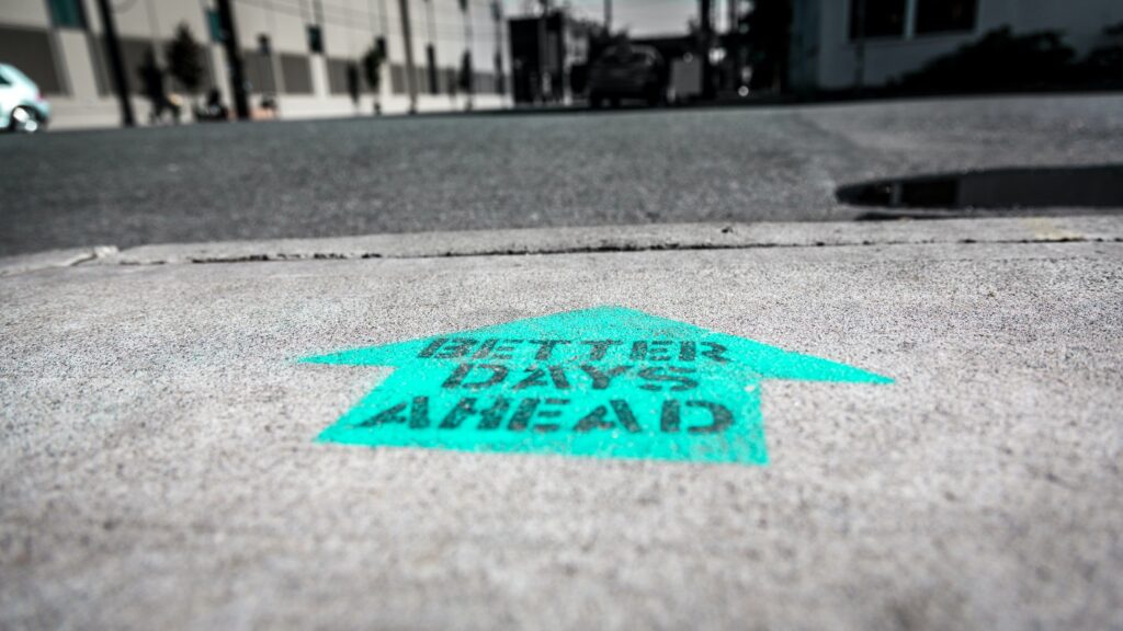 Arrow painted on sidewalk that says Better Days Ahead